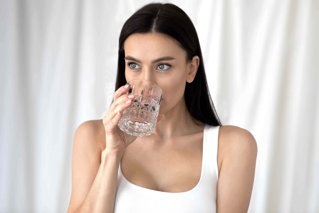 Une fille boit de l'eau pour perdre du poids avec un régime alimentaire approprié